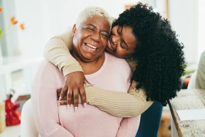 Woman hugging a smiling older adult 