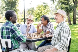 Multi-cultural group of seniors playing chess together.