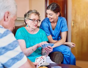 Caregiver with an older woman playing cards.