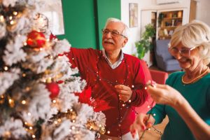 Couple of older adults decorating their Christmas tree.