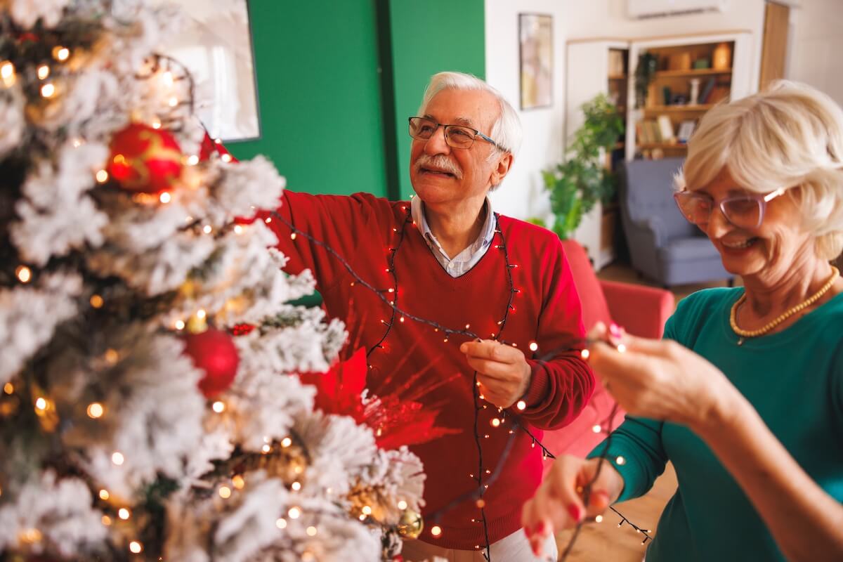 Couple of older adults decorating their Christmas tree.