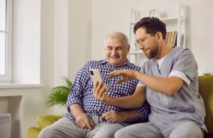 Caregiver with older man holding a smartphone