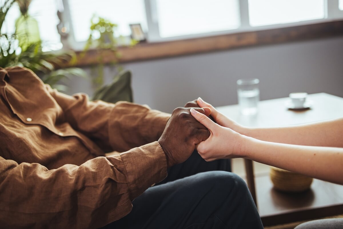 Person holding an older man's hands